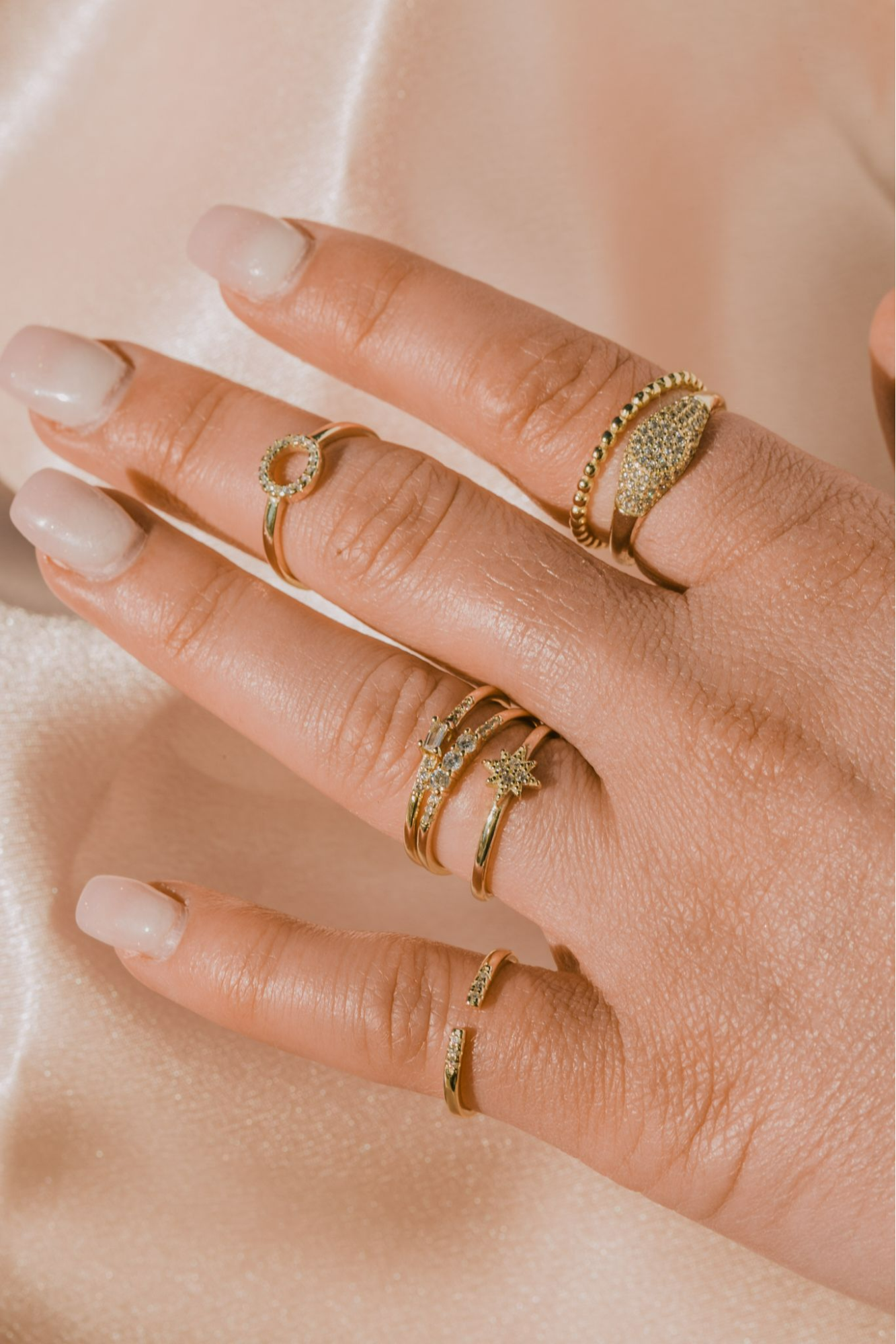 A closeup of a woman's hand wearing gold and diamond stacking rings
