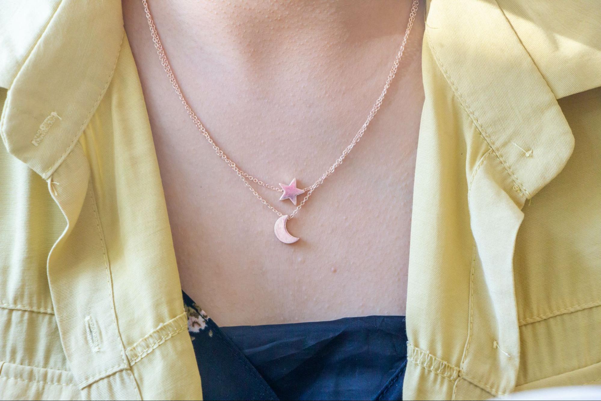 A yellow gold minimalist necklace with small moon and star charms 