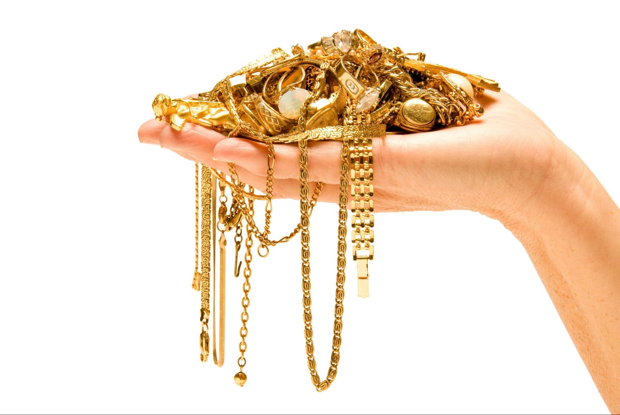 A woman holds a handful of gold jewelry to sell 