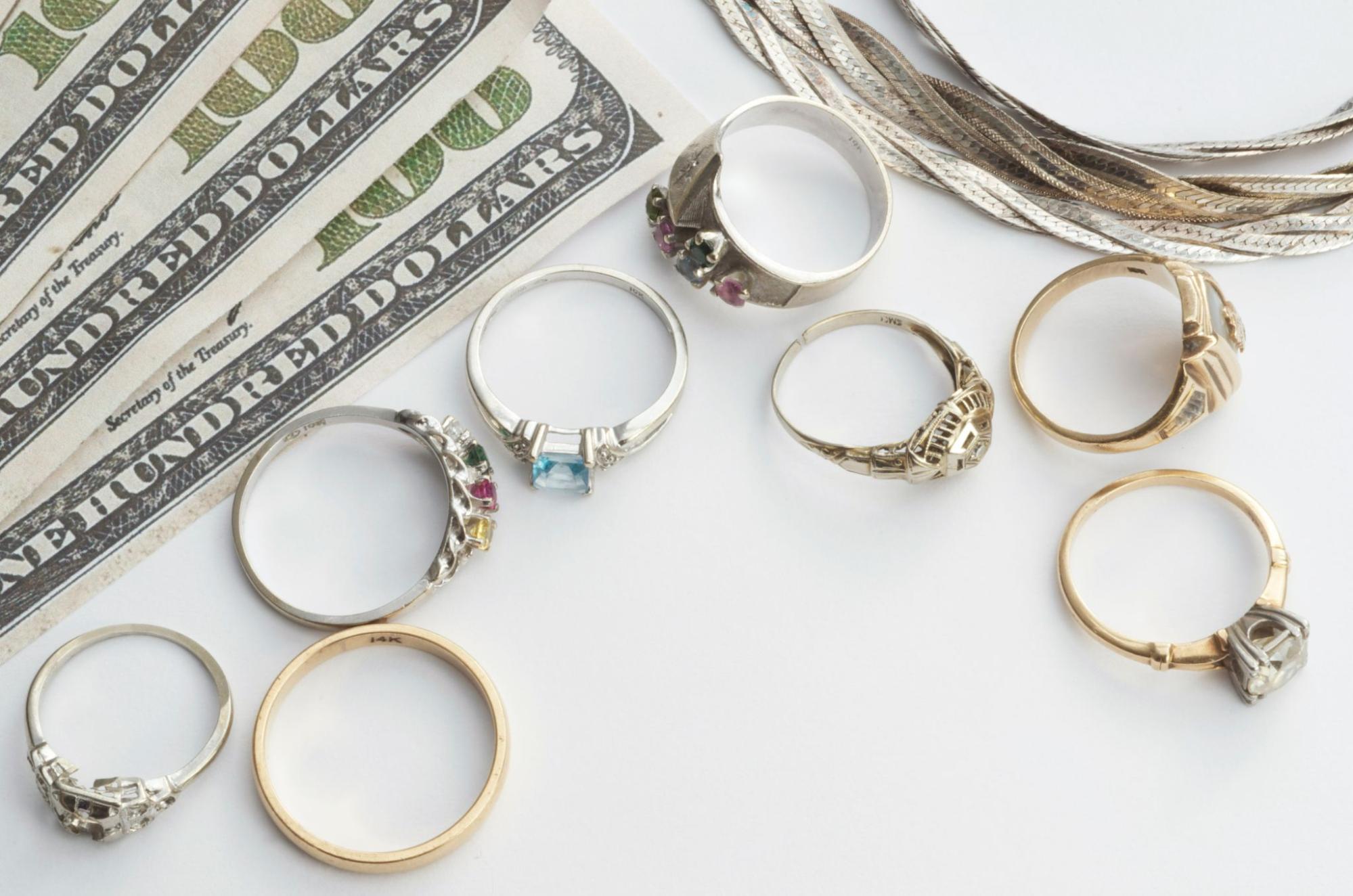 A collecttion of rings sits on a white table with cash in the background