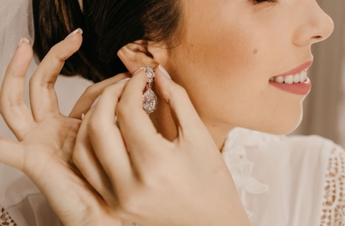 bride putting on formal earrings